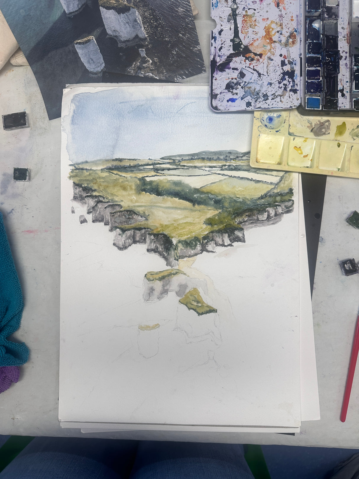 Aerial watercolour of cliffs and sea in green and blue tones