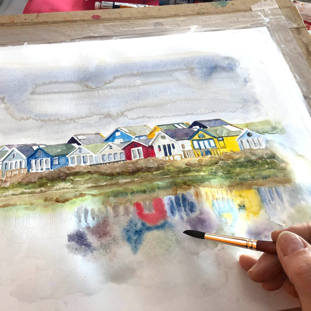 Colourful framed painting of Mudeford beach huts by Dorset artist, with whimsical style and abstract reflections.