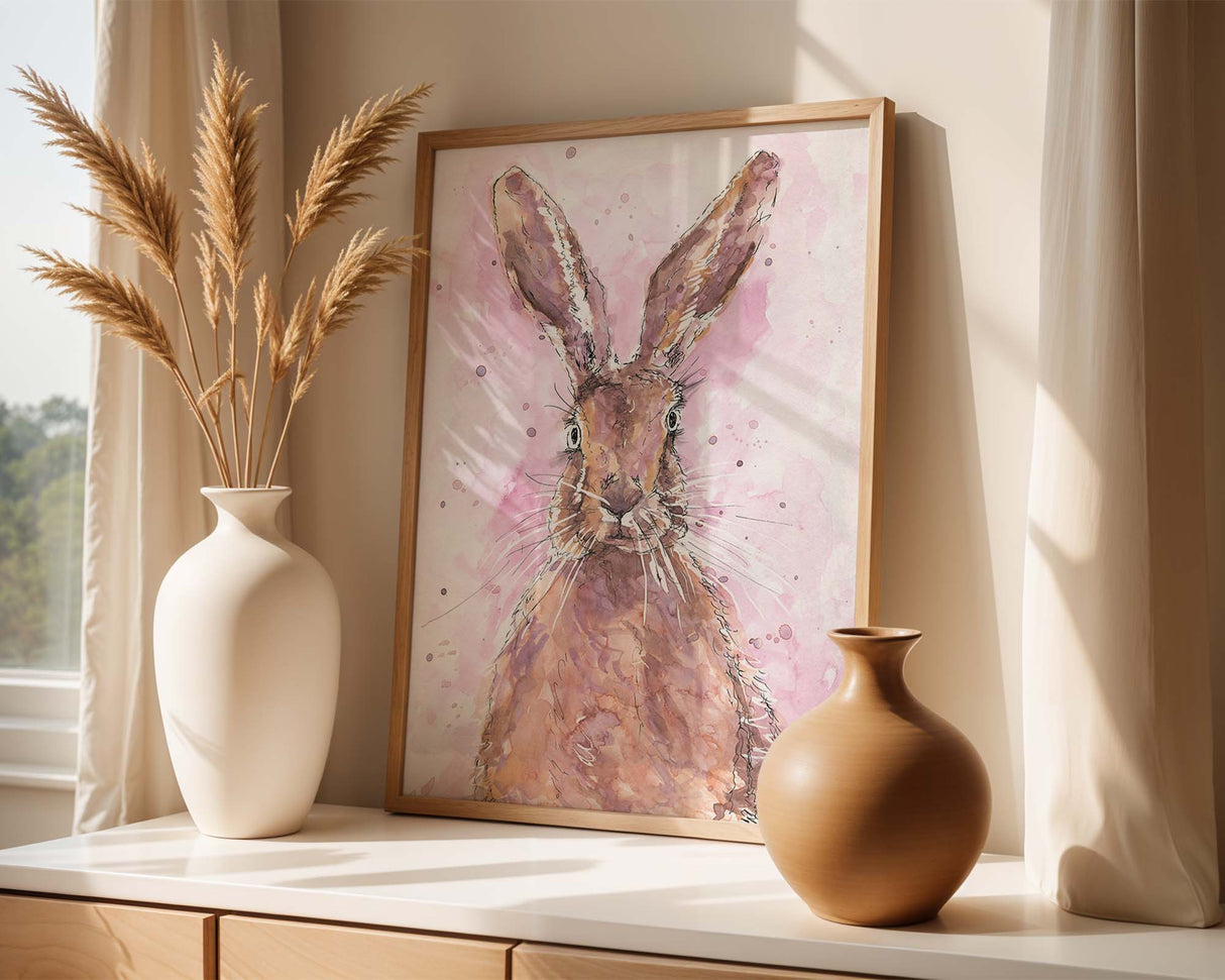 Art print of a curious hare with upright ears, surrounded by splashes of paint on a blush pink background.