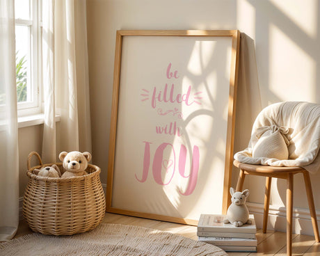 Christian nursery wall art print with pink ‘Be Filled With Joy’ text and Romans 15:13 verse on a white background.