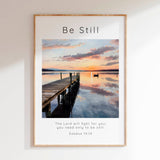 Exodus 14:14 - Be Still Bible verse print with calm lake sunset, wooden dock and small boat in soft blue and gold tones.