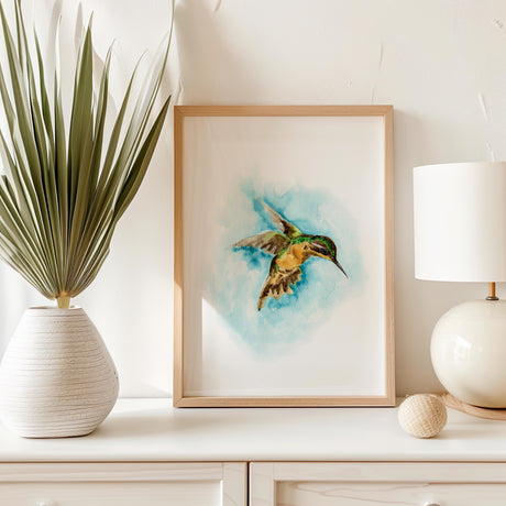 Watercolor hummingbird print featuring a green and brown bird flying through turquoise sky.