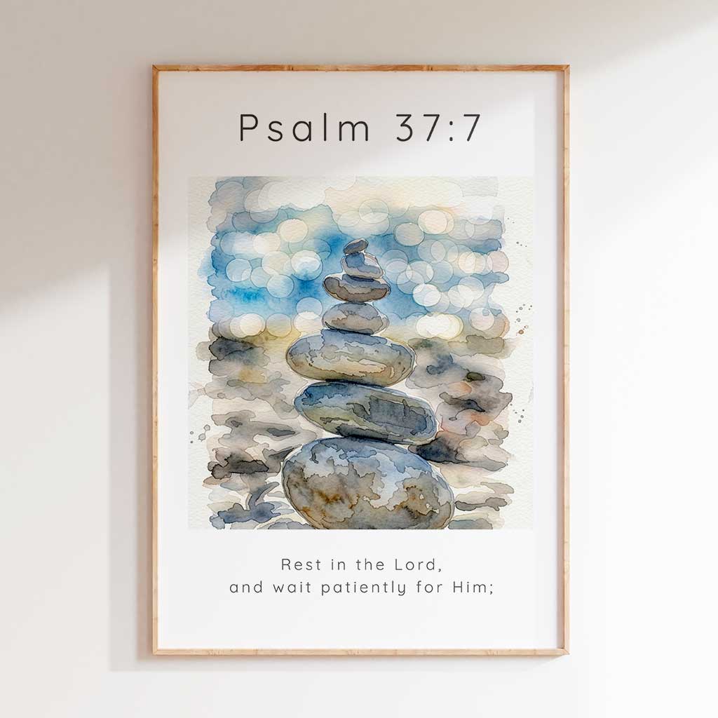 Psalm 37:7 - Rest In The Lord scripture wall art print with watercolour stacked pebbles and soft blue bokeh background.