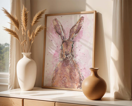 Art print of a curious hare with upright ears, surrounded by splashes of paint on a blush pink background.